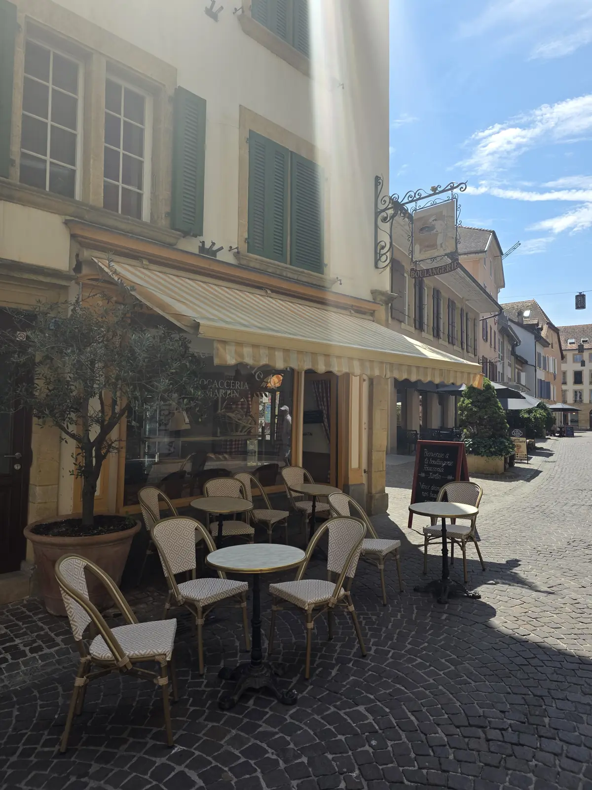 La terrasse de la boulangerie dans la rue piétonne, sous les stores jaunes